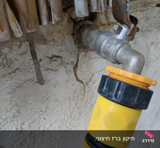 ברז מתכת עם צינור מחובר בקיר